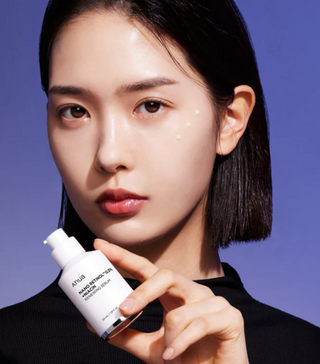 Donna con pelle luminosa applica il siero Anua Retinol 0.3% Niacinamide, trattamento viso anti-rughe ed effetto glow