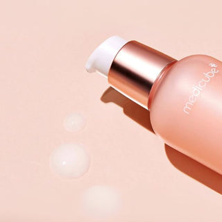 Dettaglio della texture leggera e idratante del siero MEDICUBE Triple Collagen con flacone rosa e dosatore a pompa, ideale per migliorare tonicità ed elasticità della pelle.
